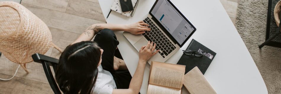 young lady typing on keyboard of laptop in living room